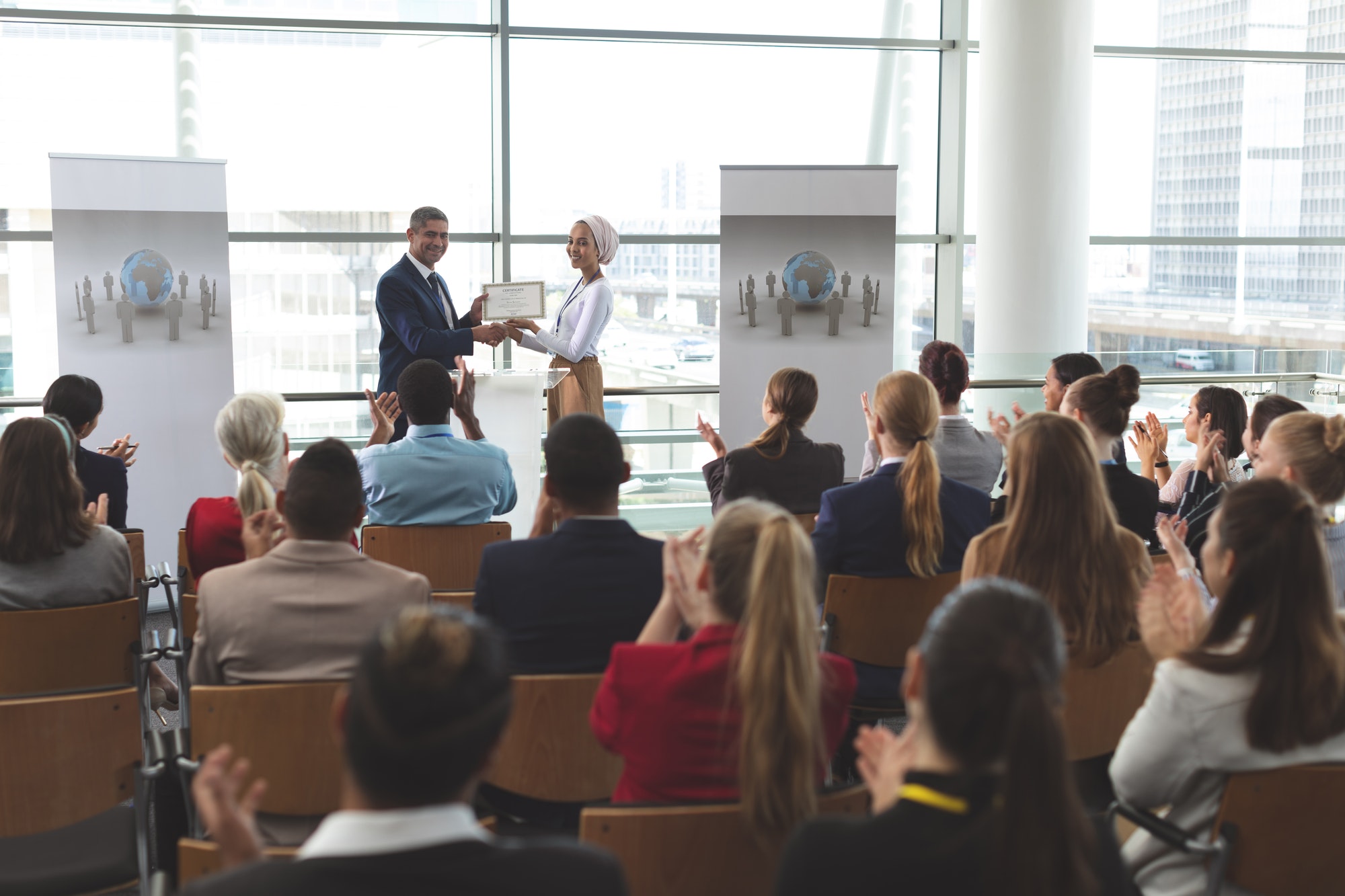businesswoman-receiving-award-from-businessman-at-business-seminar-in-office-building.jpg
